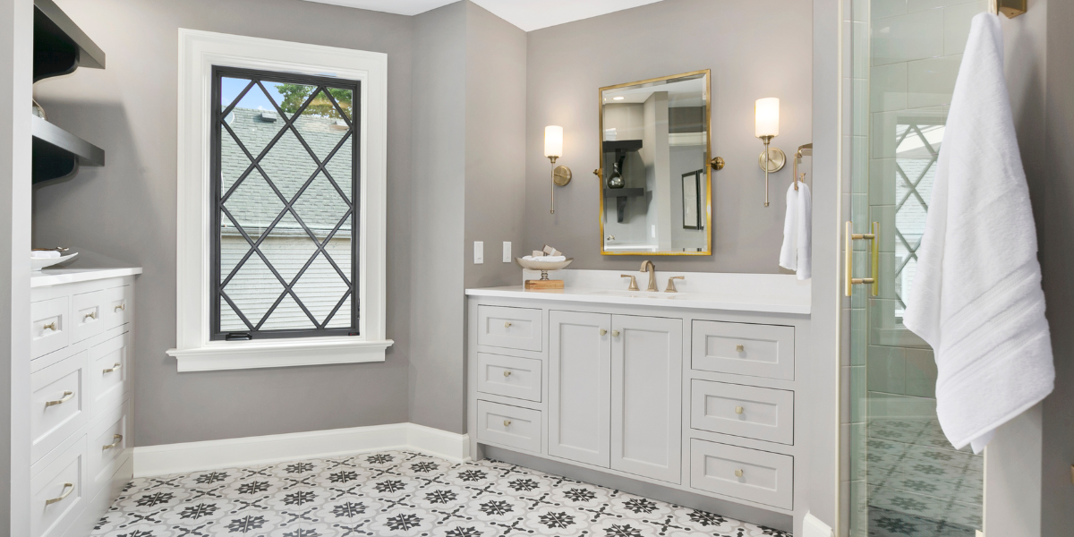 Elegant bathroom with grey cabinets, a diamond-patterned window, and a glass-enclosed shower.
