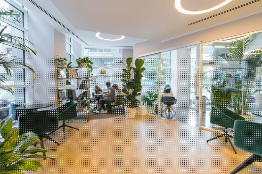 A bright, modern, and professional office space featuring a person working with sleek, futuristic technology on their desk.