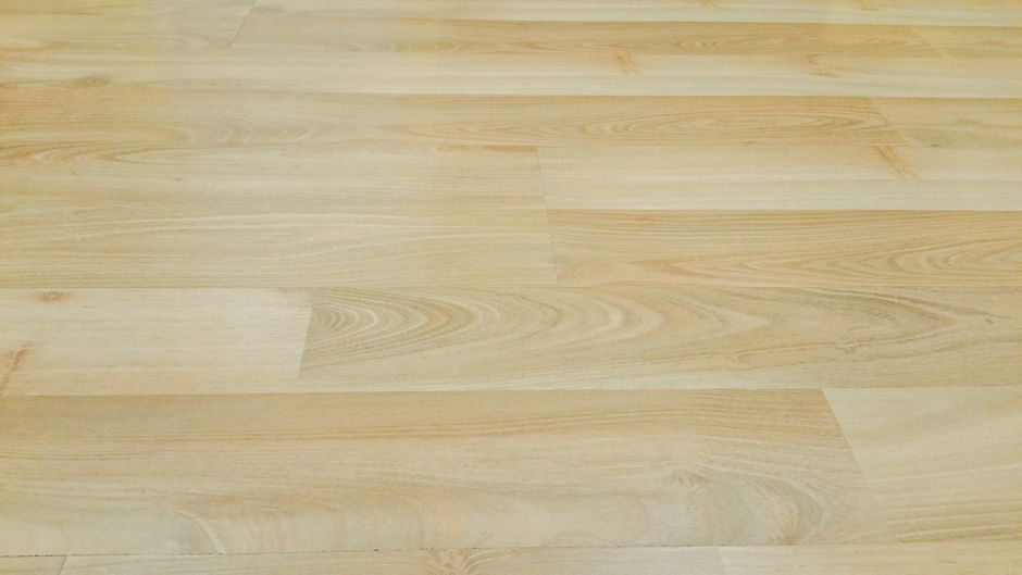 A person looking closely at wooden floorboards in a home, illustrating the act of inspecting for subtle but expensive problems like water damage or pests.